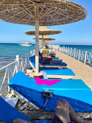 a group of blue beach chairs and umbrellas on a beach at Karma Aqua Beach in Hurghada