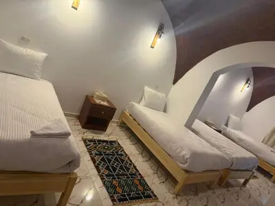 a bedroom with two twin beds and a table at ASKALEIH Nubian Guest House in Aswan