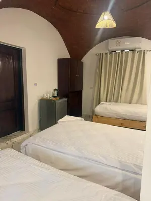 a bedroom with two beds and a window and a light at ASKALEIH Nubian Guest House in Aswan