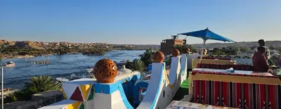 a view of a river with people sitting on a ledge at ASKALEIH Nubian Guest House in Aswan