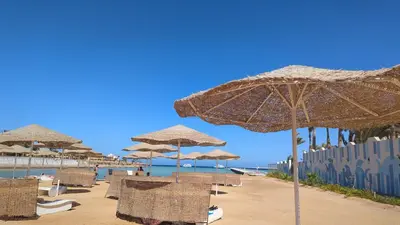 a group of chairs and umbrellas on a beach at Studio Apartment Flourenza Hurghada in Hurghada