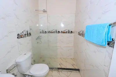 a white bathroom with a toilet and a shower at Tohamy house in Al Aqālitah