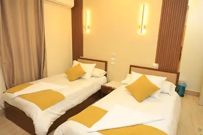 two beds in a hotel room with white and yellow pillows at Crystala 2 guest house in Aswan