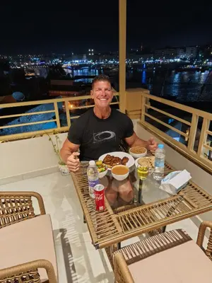a man sitting at a table with a plate of food at Crystala 2 guest house in Aswan
