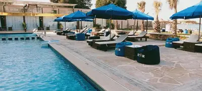 a pool with blue umbrellas and lounge chairs next to a pool at كازابلانكا ستار in Hurghada