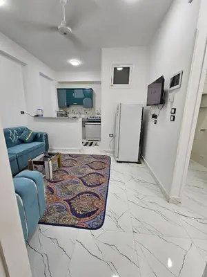 a living room with a blue couch and a refrigerator at Hatshepsut Apartments Luxor in Luxor