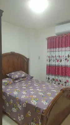 a bed with a purple comforter and a window at Elite House in Hurghada