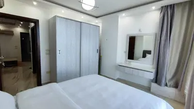 a white bedroom with a bed and a mirror at Stylish Sunny Central 1BR in Hurghada