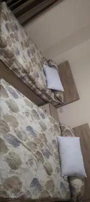 two beds in a room with a couch and pillows at جولدن طيبه الذهبيه in Hurghada