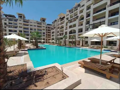 a large swimming pool with chairs and umbrellas at Aldau heights Hurghada in Hurghada