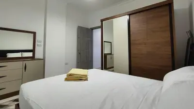 a bedroom with a white bed and a mirror at Comfort quiet central new flat in Hurghada