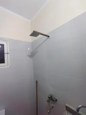 a bathroom with a white wall and a shower at Peaceful Private Studio Steps from Luxor in Luxor