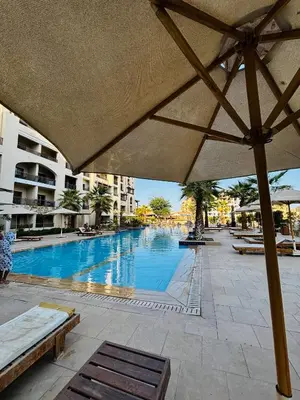 a large swimming pool in a resort with an umbrella at Prime Square Aldau Heights in Hurghada