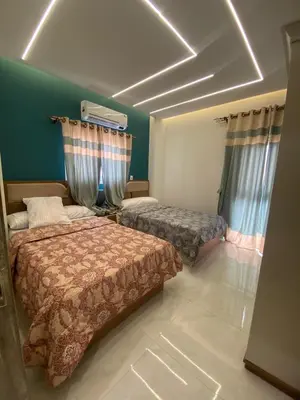 a bedroom with two beds and a green wall at Private 3 bedroom apartment in Hurghada