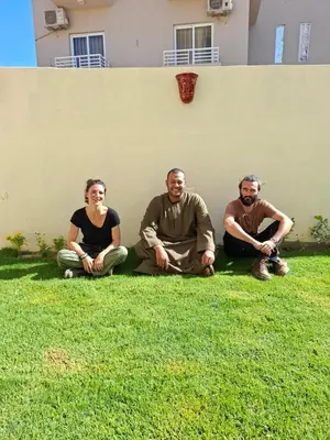 a group of three people sitting on the grass at King Nile Luxor in Luxor