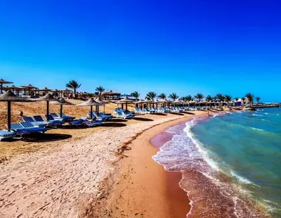 a beach with chairs and the ocean on a sunny day at Studio in Nubia Aqua Beach Twin Room in Hurghada in Hurghada