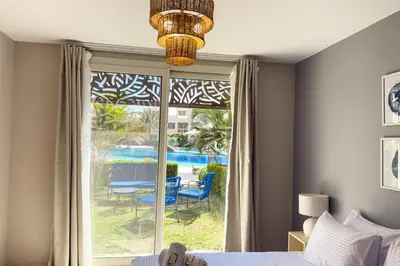a bedroom with a window with a view of a pool at The Platinum Perch 2BDR Pool View Free Pool & Beach Access in Hurghada