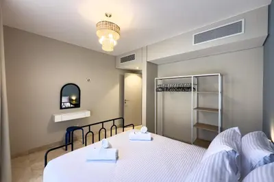 a bedroom with a bed with white sheets and a mirror at The Platinum Perch 2BDR Pool View Free Pool & Beach Access in Hurghada