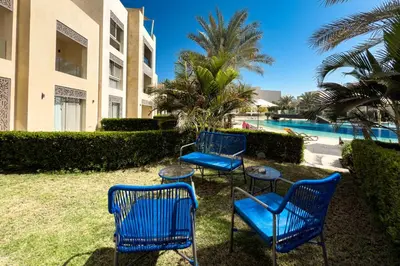 three blue chairs and tables in front of a pool at The Platinum Perch 2BDR Pool View Free Pool & Beach Access in Hurghada