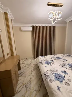 a bedroom with a bed and a desk and a chandelier at Oscar Apartment 9 in Luxor