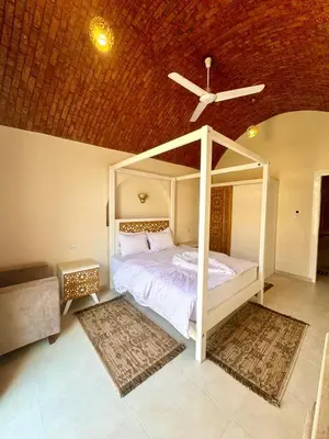 a bedroom with a white bed with a ceiling fan at Royal Home Dome Style - Ground Floor Apartment in Jazīrat al ‘Awwāmīyah