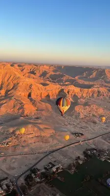 two hot air balloons are flying over the desert at Royal Home Dome Style - Ground Floor Apartment in Jazīrat al ‘Awwāmīyah