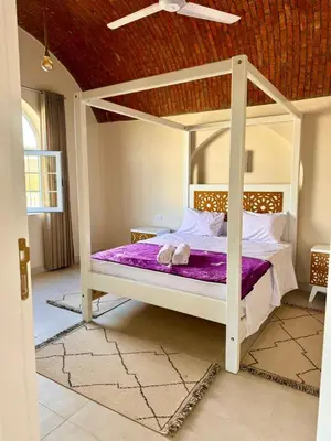 a bedroom with a white canopy bed with purple sheets at Royal Home Dome Style - Top Floor Apartment in Jazīrat al ‘Awwāmīyah