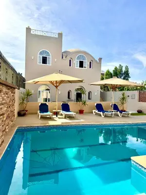 a villa with a swimming pool in front of a house at Royal Home Dome Style - Top Floor Apartment in Jazīrat al ‘Awwāmīyah