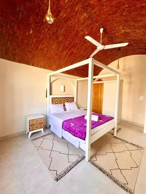 a bedroom with a white bed with purple sheets at Royal Home Dome Style - Top Floor Apartment in Jazīrat al ‘Awwāmīyah