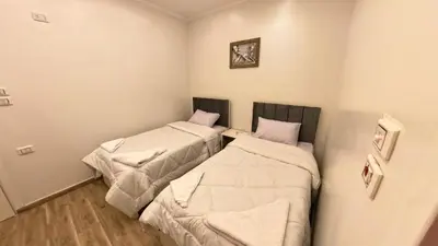 two beds in a room with white walls at Celia Guest House in Luxor