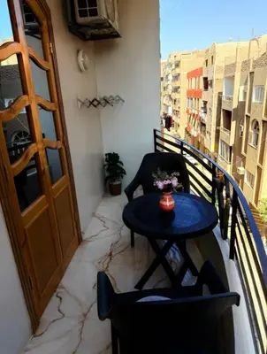 a balcony with a small table and a door at Oscar Apartment 8 in Luxor