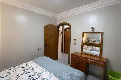 a bedroom with a bed and a dresser and a mirror at Oscar Apartment 10 in Luxor