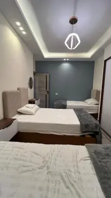 a bedroom with two beds and a light fixture at شقة فندقية امام المارينا 3 غرف 5 سراير in Hurghada