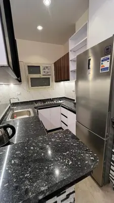 a kitchen with granite counter tops and a refrigerator at شقة فندقية امام المارينا 3 غرف 5 سراير in Hurghada