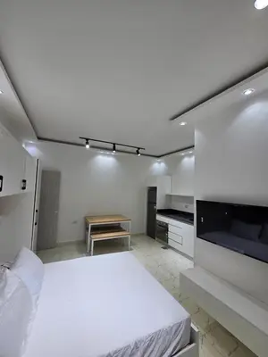 a white bedroom with a bed and a tv at Modern Studio with Pool and Private Beach Access in Hurghada