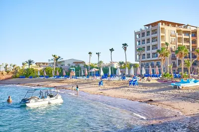 a boat in the water on a beach with a building at Juliana Golden Beach Resort in Hurghada