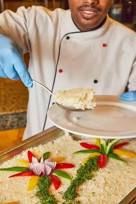 a chef is holding a plate with a piece of food at Juliana Golden Beach Resort in Hurghada