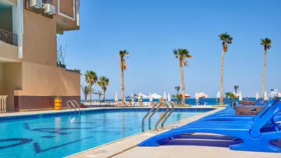 a swimming pool with palm trees in a resort at Juliana Golden Beach Resort in Hurghada
