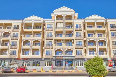 a large building on a street with cars parked in front at Juliana Golden Beach Resort in Hurghada
