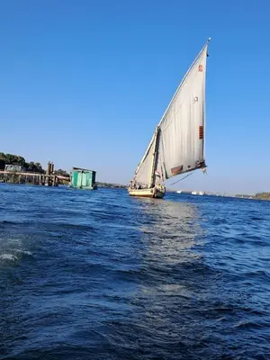 a white sail boat on the water with a dock at Traditional Felucca Sailing Boat Overnight in Aswan