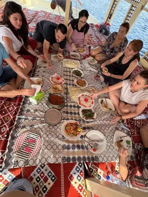 a group of people sitting around a table with food at Traditional Felucca Sailing Boat Overnight in Aswan