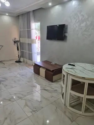 a living room with a table and a tv on a wall at Happy Home Hurghada in Hurghada