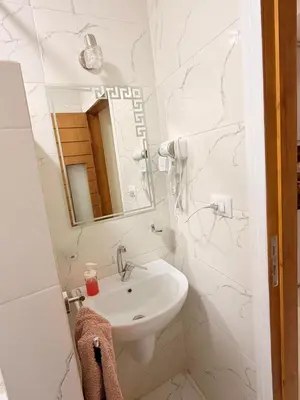 a white bathroom with a sink and a mirror at Oscar apartment 5 in Luxor