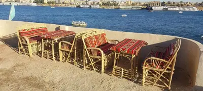 a group of chairs sitting on a wall next to the water at Nile Domes Guest House in Luxor