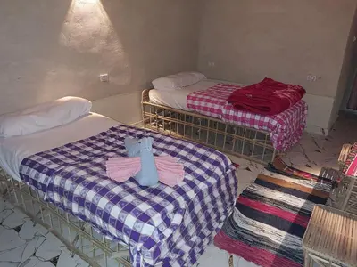 two beds in a room with a teddy bear on the bed at Nile Domes Guest House in Luxor