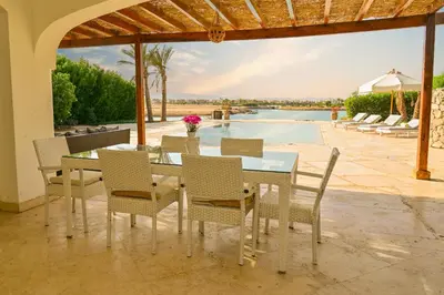 a dining room with a table and chairs and a pool at Breathtaking Villa in El Gouna 15 in Hurghada