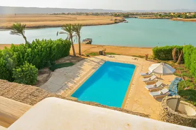 an overhead view of a swimming pool with chairs and an umbrella at Breathtaking Villa in El Gouna 15 in Hurghada
