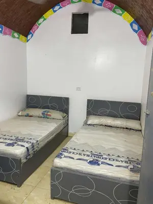 two beds in a room with an arch over them at منزل نوبي إضافة in Aswan