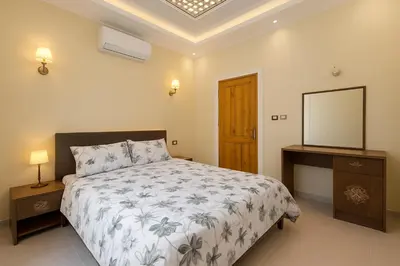 a bedroom with a bed and a dresser and a mirror at Oscar Apartment 2 in Luxor