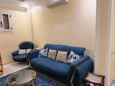 a living room with a blue couch and a table at Oscar Apartment 2 in Luxor